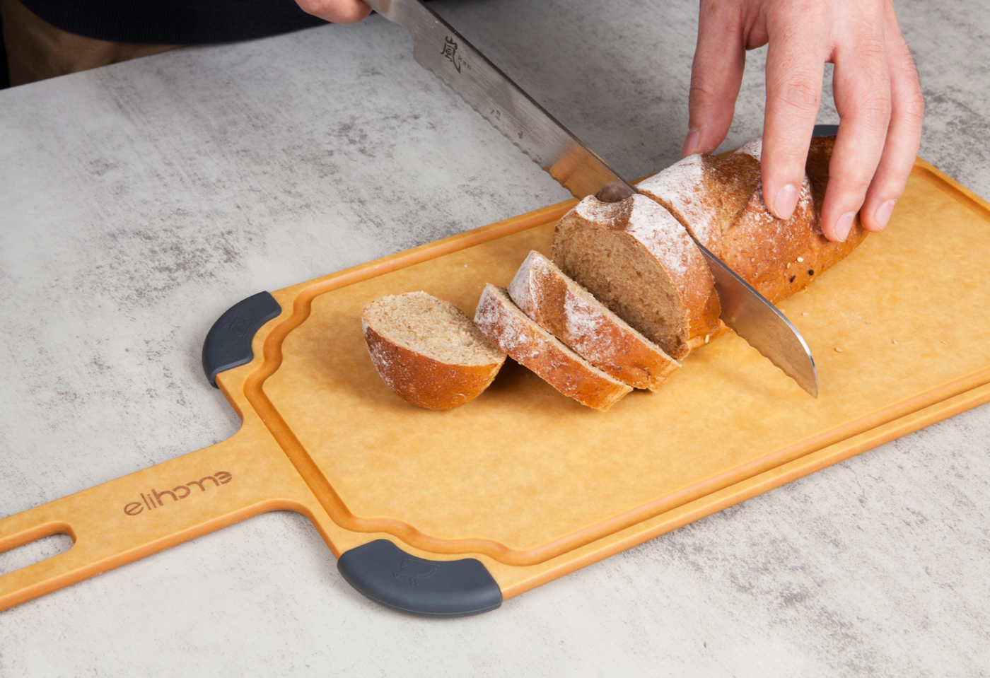 Elihome non-toxic dishwasher safe wood fiber cutting board with handle, slicing fresh bread on a kitchen countertop