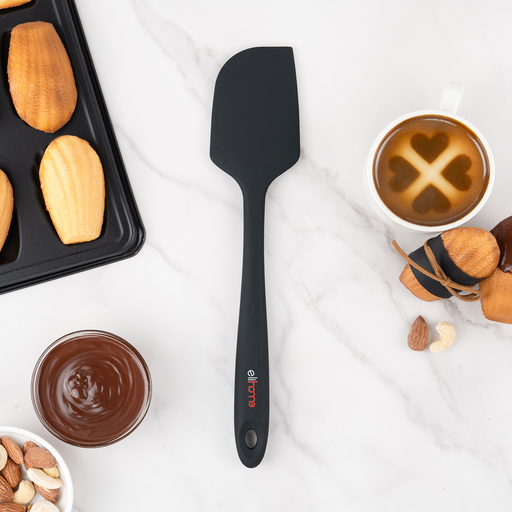 Elihome Classic silicone spatula in Black on a marble counter beside a tray of madeleines, a bowl of melted chocolate and a cup of coffee