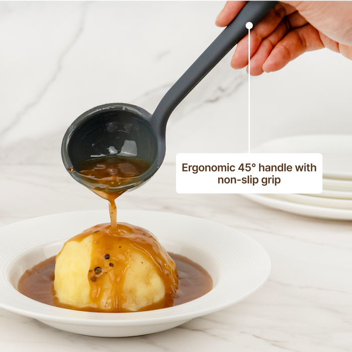 Hand using the Elihome Classic Ladle in Gray to pour gravy over a dumpling, ergonomic 45 degree handle with non-slip grip