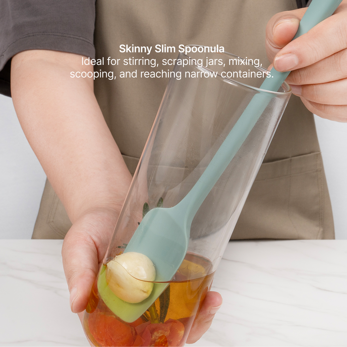 Elihome Skinny Slim Silicone Spoonula from the silicone kitchen tool set in use, reaching fruit at the bottom of a tall glass