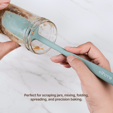 Hands using an Elihome Skinny Slim silicone spatula in Sage Green to scrape the inside of a glass jar, perfect for scraping jars, mixing, folding, spreading and precision baking