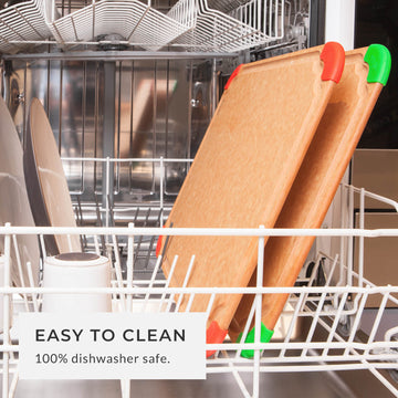 Two fiber wood cutting boards with red and green corners placed inside a dishwasher rack, showing the 100% dishwasher safe and easy-to-clean design.